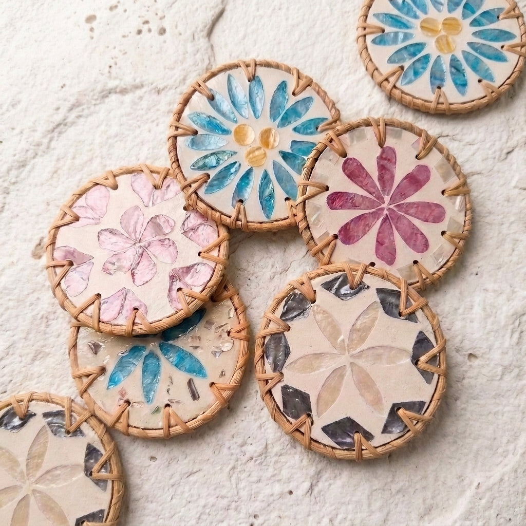 A group of round woven straw coasters with colorful floral and geometric designs, arranged on a textured off-white surface by Bamboo Switch