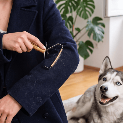 a woman removes lint from her coat as her pet dog observes in the background | Bamboo Switch