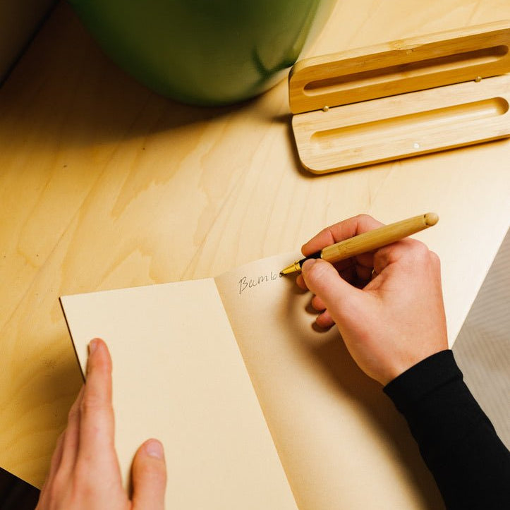 bamboo pen being used to write in a bamboo notebook with the open pen case behind | Bamboo Switch