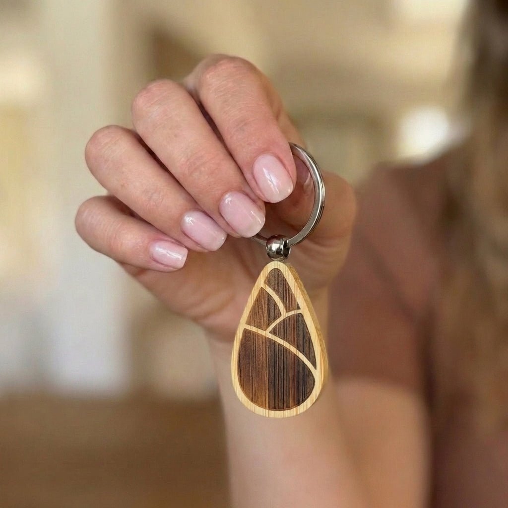 Hand holding a bamboo keychain with a blurred background