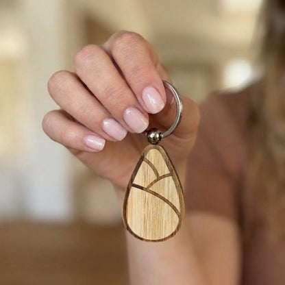 Hand holding a bamboo keychain with a blurred background