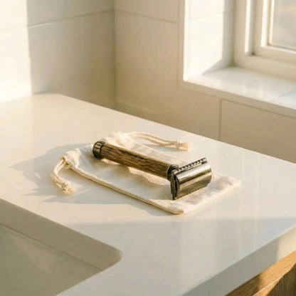 A vintage-style metal and bamboo roller with a cream drawstring pouch, resting on a white bathroom counter near a window by Bamboo Switch