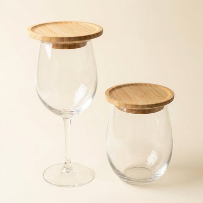 Two clear glass containers with bamboo lids, one shaped like a wine glass and one like a short jar, on a warm beige background by Bamboo Switch