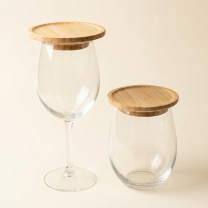 Two clear glass containers with bamboo lids, one shaped like a wine glass and one like a short jar, on a warm beige background by Bamboo Switch