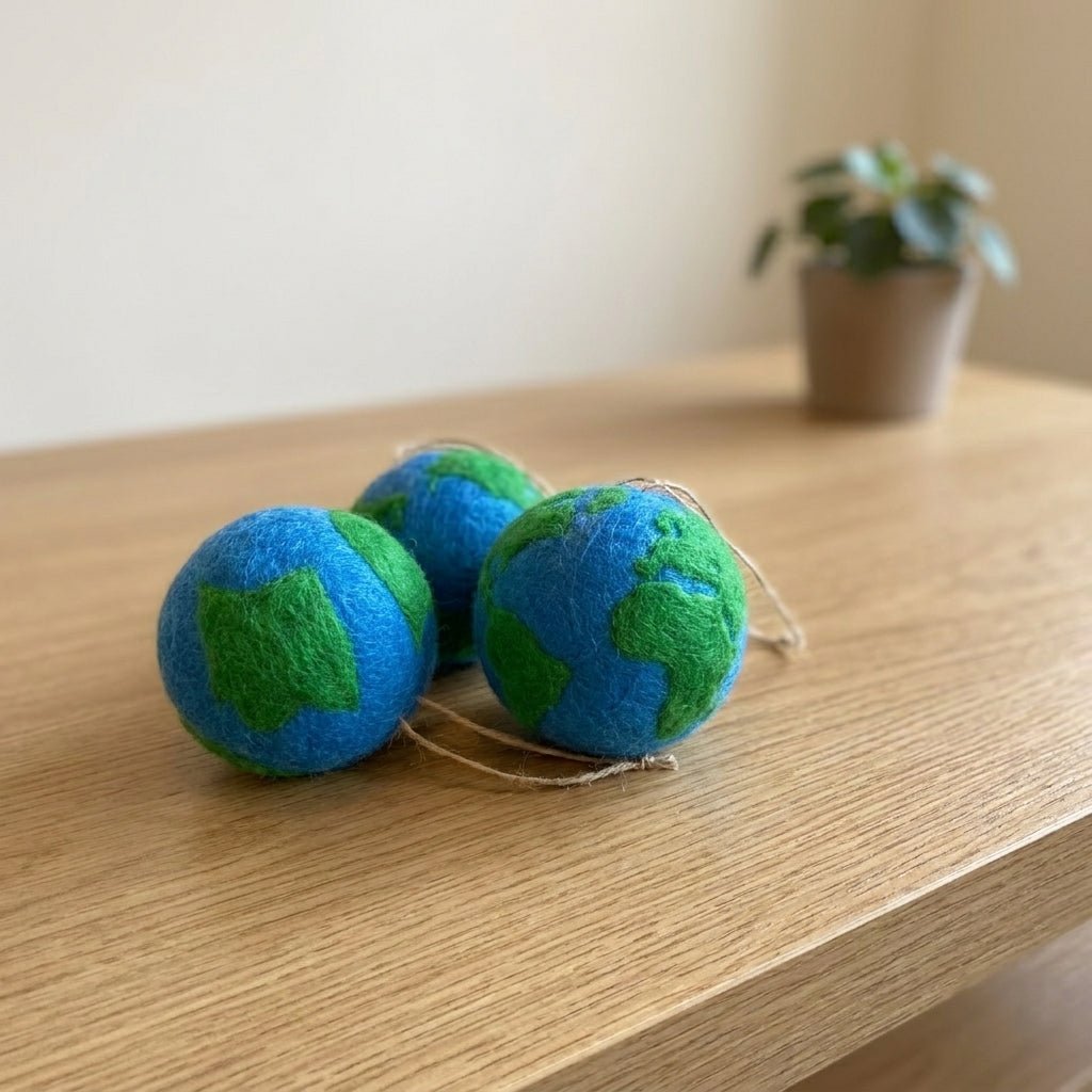 Three Earth-themed balls on a wooden surface with a plant in the background